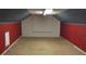 Spacious attic with red walls and carpet flooring, offering potential for storage or conversion into a unique living space at 3581 Midway Rd, Decatur, GA 30032