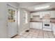 Bright kitchen featuring white cabinets and appliances, with a door to the outside and neutral tile flooring at 3581 Midway Rd, Decatur, GA 30032