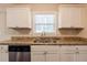 This kitchen features a stainless steel dishwasher, granite countertops, white cabinetry, and a window above the sink at 5130 Cornwallis Ct, Stone Mountain, GA 30088