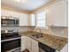Corner view of a kitchen highlighting granite countertops, stainless appliances, and white cabinetry at 3499 Villa Se Cir, Atlanta, GA 30354