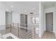 Upstairs hallway with wood and black metal railing, contemporary chandelier, and large windows at 734 Riverside Rd, Sugar Hill, GA 30518