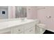 Well-lit bathroom featuring a white vanity, toilet, and pink walls, creating a clean and simple aesthetic at 559 Fairway Dr, Woodstock, GA 30189