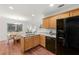 Efficient kitchen with wood cabinets, black appliances, open to the dining area with sliding glass doors at 5935 Mountain Top Pl, Cumming, GA 30041