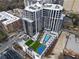 Aerial view of a high-rise building with pool, lounge area, tennis court, and green spaces at 2425 Peachtree Rd # 1806, Atlanta, GA 30305