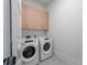 A well-lit laundry room featuring a modern washer and dryer, with overhead wood cabinets for storage at 2425 Peachtree Rd # 1806, Atlanta, GA 30305