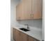 Bright laundry area featuring light wood cabinetry, quartz countertops, and a stainless steel sink at 2425 Peachtree Rd # 1806, Atlanta, GA 30305