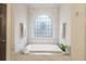 Relaxing bathroom featuring a soaking tub and an arched window at 10635 N Edgewater Pl, Johns Creek, GA 30097