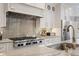 Close-up of a kitchen with stainless steel appliances, a gray backsplash, and marble countertops at 10635 N Edgewater Pl, Johns Creek, GA 30097