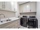 Well-organized laundry room with upper cabinets, washer, dryer, and sink with marble countertop at 10635 N Edgewater Pl, Johns Creek, GA 30097