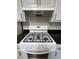 Close up on gas range with overhead vent and white cabinets at 3817 Paces Ferry West, Atlanta, GA 30339