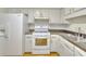 Well-lit kitchen featuring white appliances and ample cabinet space above the gas range and sink at 3817 Paces Ferry West, Atlanta, GA 30339