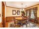 Elegant dining room features wood floors, a wooden table and chairs, complemented by wainscoting and decorative curtains at 1824 Colonial South Sw Dr, Conyers, GA 30094