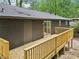 Exterior view of home showcasing wooden deck, siding, and door leading to the yard with lush green trees at 2210 Bolling Brook Sw Dr, Atlanta, GA 30311