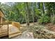 View of wooden deck and backyard landscape including stone wall, surrounding trees, and a walking path at 2210 Bolling Brook Sw Dr, Atlanta, GA 30311