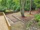 View of wooden deck and backyard landscape with greenery, trees, and a stone retaining wall at 2210 Bolling Brook Sw Dr, Atlanta, GA 30311