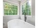 Bright bathroom features a soaking tub, matte black fixtures, and natural light from two large windows at 274 Westchester Club Dr, Hiram, GA 30141