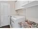 Convenient laundry room with washer, dryer, storage cabinets, and an ironing board at 274 Westchester Club Dr, Hiram, GA 30141