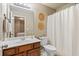 Well-lit bathroom featuring a wood vanity, a white toilet, and a shower with a white curtain at 3830 Deer Run Dr, Cumming, GA 30028