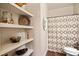 Cozy bathroom featuring floating shelves, a decorative mirror, and a patterned shower curtain at 3830 Deer Run Dr, Cumming, GA 30028