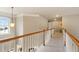 Bright hallway featuring carpet flooring, wood railings, and a large window offering natural light at 3830 Deer Run Dr, Cumming, GA 30028