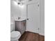 A half-bathroom with wood flooring and a toilet is adjacent to a modern grey vanity at 3046 Wendgate Dr, Marietta, GA 30062