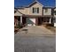 Two-story tan home with brick facade, and a concrete driveway leading to an attached garage at 233 Tara Commons Walk, Loganville, GA 30052
