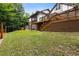 Expansive backyard with lush greenery, a wooden deck, and steps leading to an upper-level porch at 3996 Spalding Ln, Atlanta, GA 30350