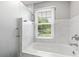 Bathroom with a window over a white tub with clear glass partition and marble surround at 3996 Spalding Ln, Atlanta, GA 30350