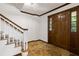A welcoming foyer featuring stone floors, a stained wood door, and a staircase with white banisters at 3996 Spalding Ln, Atlanta, GA 30350