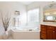 Cozy bathroom with corner tub, tiled surround, and decorative window at 2322 Norbury Se Cv, Smyrna, GA 30080