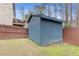 This backyard features a blue storage shed, a fence, and grass, perfect for outdoor storage at 3739 Newhalem Sw St, Atlanta, GA 30331