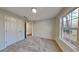 Neutral-toned bedroom featuring plush carpet, a bright, minimalist design, and a large window at 285 Belmont Trl, Covington, GA 30016