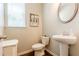 Stylish powder room with a pedestal sink, decorative mirror, and natural light at 113 Maplewood Ln, Conyers, GA 30094