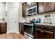 Modern kitchen with stainless steel oven, dark wood cabinets, gray backsplash, and granite countertops at 113 Maplewood Ln, Conyers, GA 30094