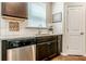 Close-up of the kitchen sink featuring granite countertops, a stainless steel dishwasher, and dark cabinetry at 113 Maplewood Ln, Conyers, GA 30094