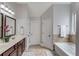 Bathroom featuring double vanity with dark cabinets, a soaking tub, and decorative mirrors and light fixtures at 1217 Trophy Club Ave, Dacula, GA 30019