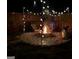 Beautiful outdoor fire pit area at night, surrounded by string lights and stone pavers at 6048 Prodigy Ln, Locust Grove, GA 30248