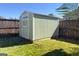 Backyard shot of a shed with light green vinyl siding, located on a grassy lawn, bordered by a wooden fence at 6048 Prodigy Ln, Locust Grove, GA 30248
