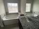 Bright bathroom with a soaking tub, dark vanity with granite counters, and a large window at 5021 Falcon Pt, Douglasville, GA 30135