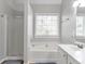 Bright bathroom featuring a bathtub, shower, window, and neutral color tones at 4265 Elmhurst Ln, Cumming, GA 30028