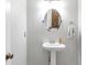 Clean and modern powder room featuring a pedestal sink and decorative mirror at 4265 Elmhurst Ln, Cumming, GA 30028