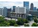 View of the Colony House condo building nestled among mature trees and featuring a stunning city skyline backdrop at 145 15Th Ne St # 1012, Atlanta, GA 30309