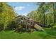 Backyard features a home with tiered decking surrounded by lush trees and green grass at 2057 Sugar Pike Rd, Woodstock, GA 30188