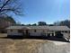 Ranch-style home with gray roof, carport, and mature trees, all under a bright blue sky at 1729 James Burgess Rd, Suwanee, GA 30024