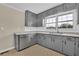 Clean kitchen showcasing stainless steel dishwasher, gray cabinets, and bright window at 1729 James Burgess Rd, Suwanee, GA 30024