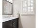 Modern bathroom featuring a sleek black vanity with marble countertop and window with white shutters at 7215 Gresham Trce, Cumming, GA 30040