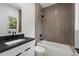 Modern bathroom featuring a sleek vanity with black countertop and a tiled shower-tub combo with glass partition at 1186A Francis Nw St, Atlanta, GA 30318