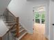 Hallway with hardwood floors, wooden staircase with black railings and an open door showcasing the view at 1186A Francis Nw St, Atlanta, GA 30318