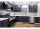 Modern kitchen featuring stainless steel appliances, navy cabinets, white countertops, and hardwood floors at 6487 Grey Fox Way, Riverdale, GA 30296