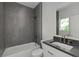 Modern bathroom featuring sleek gray tile, a soaking tub, and a stylish vanity with black countertop at 1186B Francis Nw St, Atlanta, GA 30318